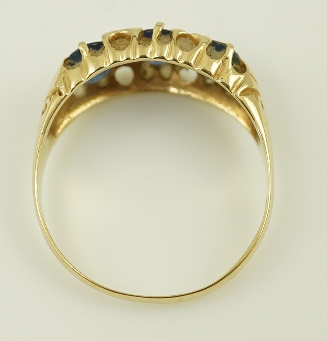 An Edwardian 15ct gold and three stone oval cut sapphire set half hoop ring, with diamond chip spacers, size Q, gross weight 2.4 grams. Condition - poor to fair